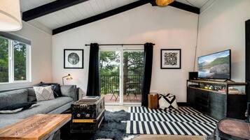 A modern living room with a sofa, a wooden coffee table, a television, and a black and white striped rug.