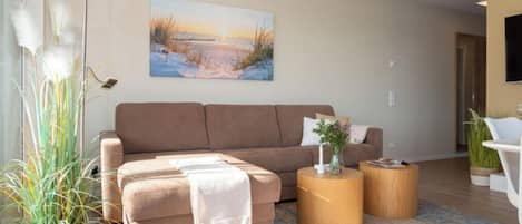 En moderne stue med sofa, sofabord og et maleri på væggen.