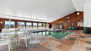 A pool area with lounge chairs and a table, surrounded by wooden walls and large windows. - Bear Ridge by Avantstay Smoky Views + Indoor Pool + Sauna & Spa Near Park Trails (Gatlinburg)