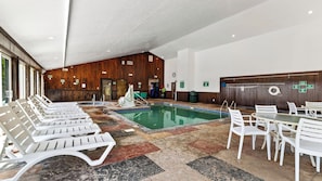 Ein Poolbereich mit Liegestühlen und Tischen, Holzwänden und einem gefliesten Boden.