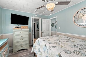 A bedroom with a bed, dresser, ceiling fan, and a wall-mounted TV. - Saltwater Shanty GolfCart•Linens•OceanLakes (Horry County)