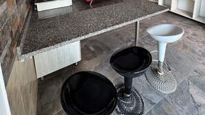 A compact kitchen with a gas stove, a red sofa, and a white pedestal sink. - HOTEL PALM BAY  (Bello horizonte SANTA MARTA)