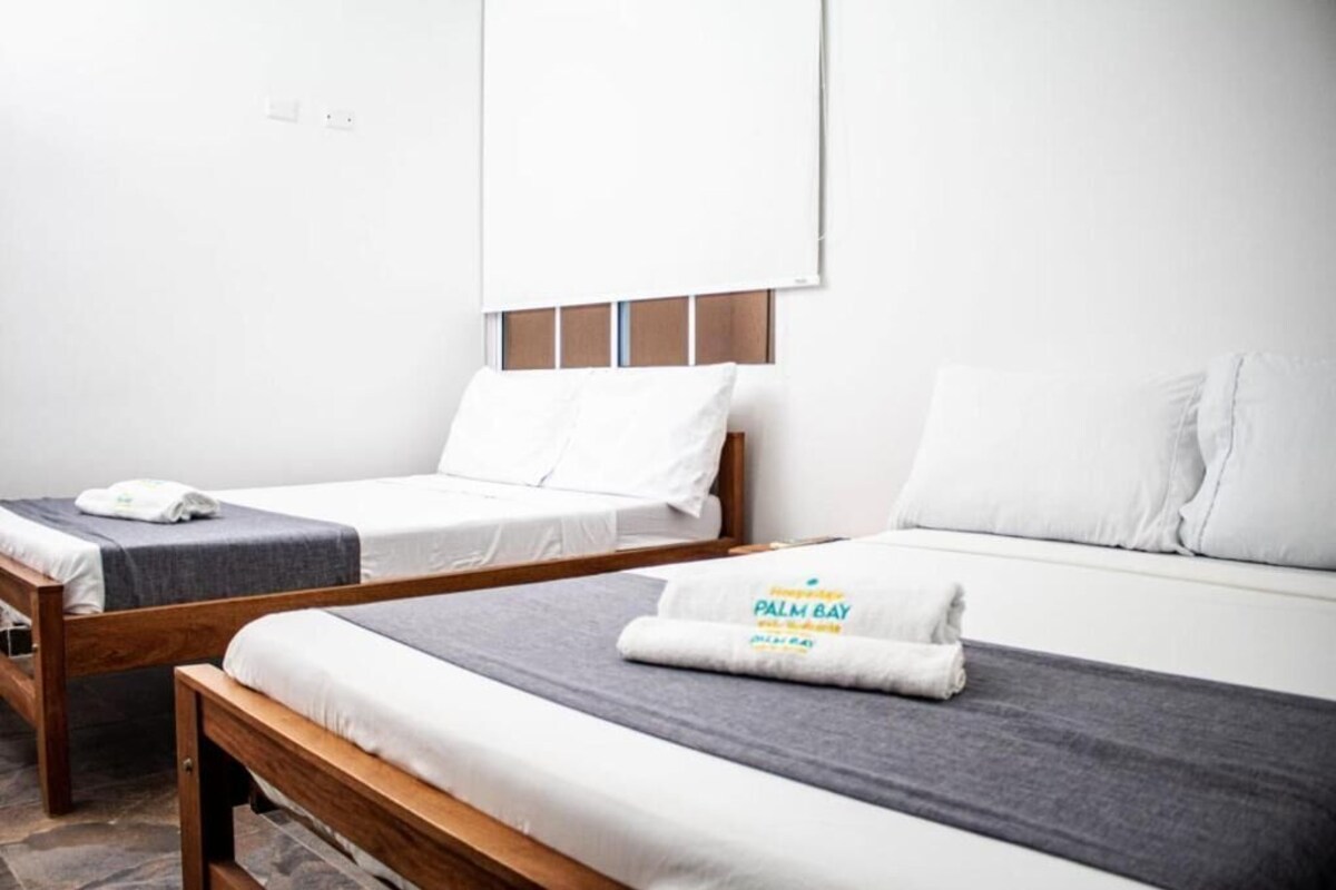 Een hotelkamer met twee enkele bedden, een houten hoofdbord en een grijze deken.