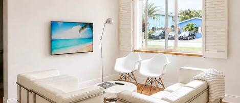 Un salon moderne avec une grande fenêtre, un téléviseur à écran plat, un canapé et une table basse.