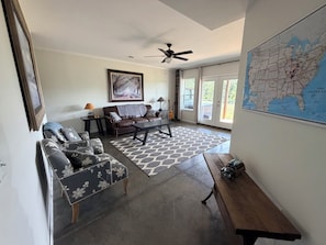 A spacious living room with a sofa set, a coffee table, and a map on the wall.