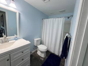 Baño con lavamanos blanco, inodoro y cortina de ducha.