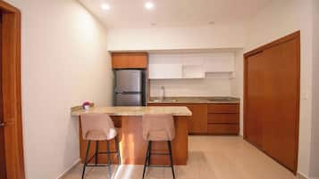 A compact kitchen with a built-in refrigerator, a sink, and two bar stools.