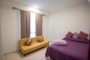 A bedroom with a sofa and a bed, both with pillows.