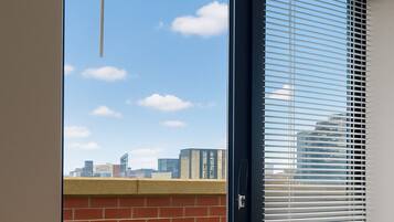 A room with a sliding glass door leading to an outdoor balcony with a view of the city skyline.