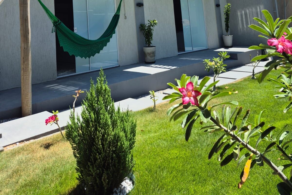 A modern two-story building with balconies, a hammock, and potted plants.