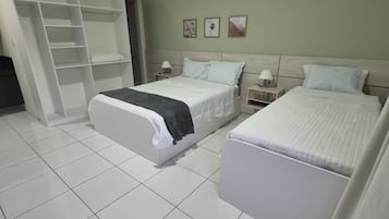 A hotel room with a large bed, a smaller bed, a wardrobe, and a nightstand with a lamp.