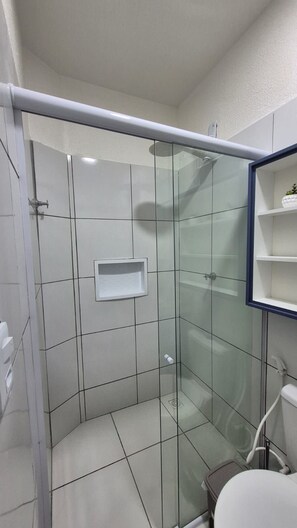 Een compacte, afgesloten douchecel met een glazen deur, een witte wastafel en een toilet.
