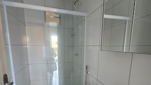 A bathroom with a toilet, a sink, and a shower enclosure. - Residencial New Stilo (Aracati)