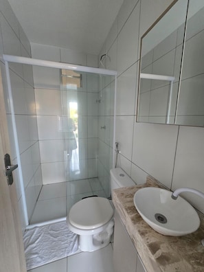 A bathroom with a toilet, a sink, and a shower enclosure. - Residencial New Stilo (Aracati)