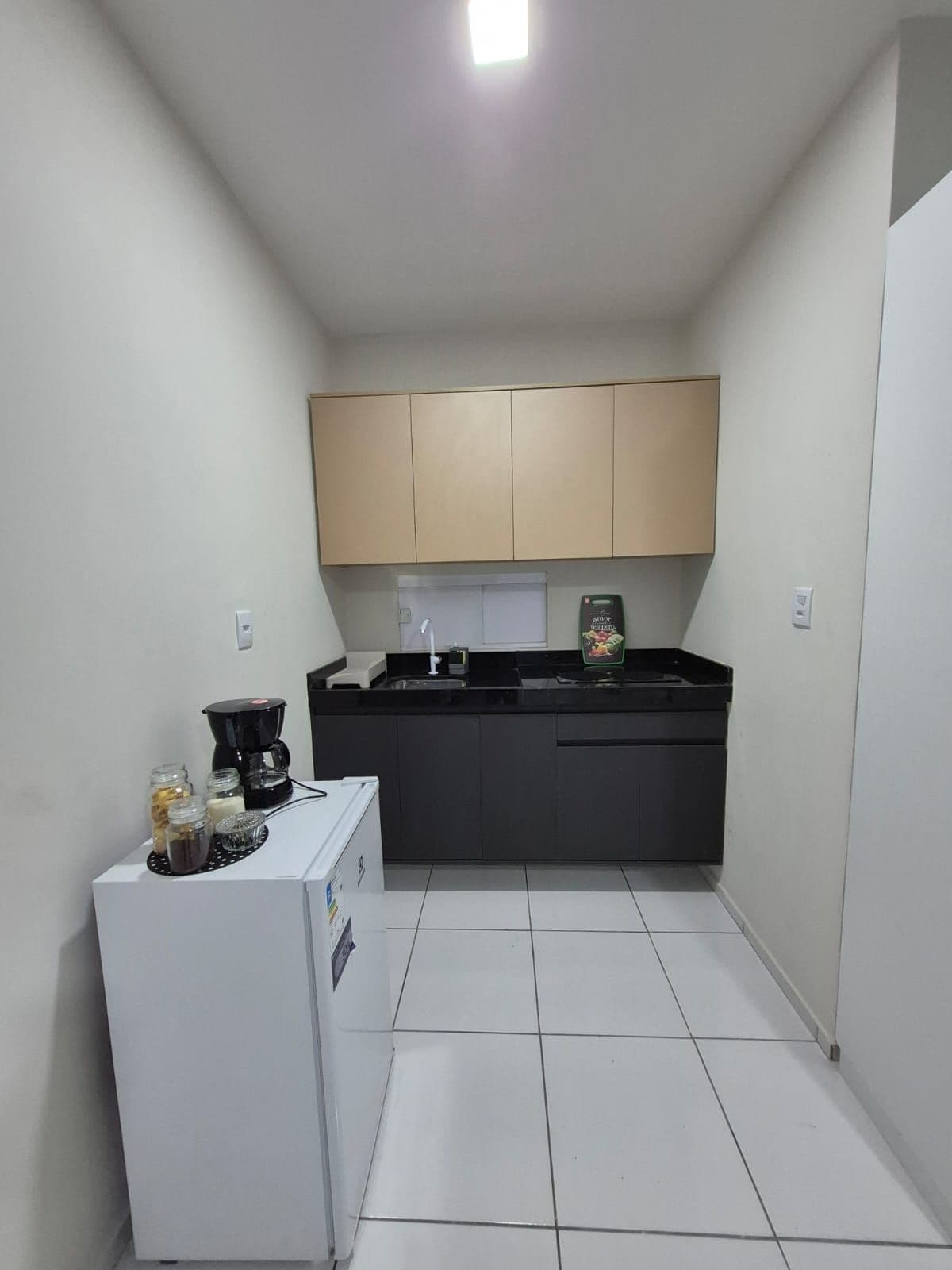 A compact kitchen with a refrigerator, a coffee maker, and a sink.