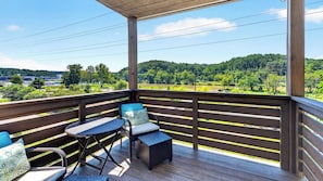 A covered outdoor deck with a view of a green landscape and a body of water. - Riverside House by Avantstay French Broad River Views Balcony Near DT + Silver Line Park (Asheville)