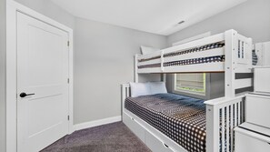 Ein Zimmer mit einem Etagenbett, einer Tür und einem Fenster mit Jalousien.