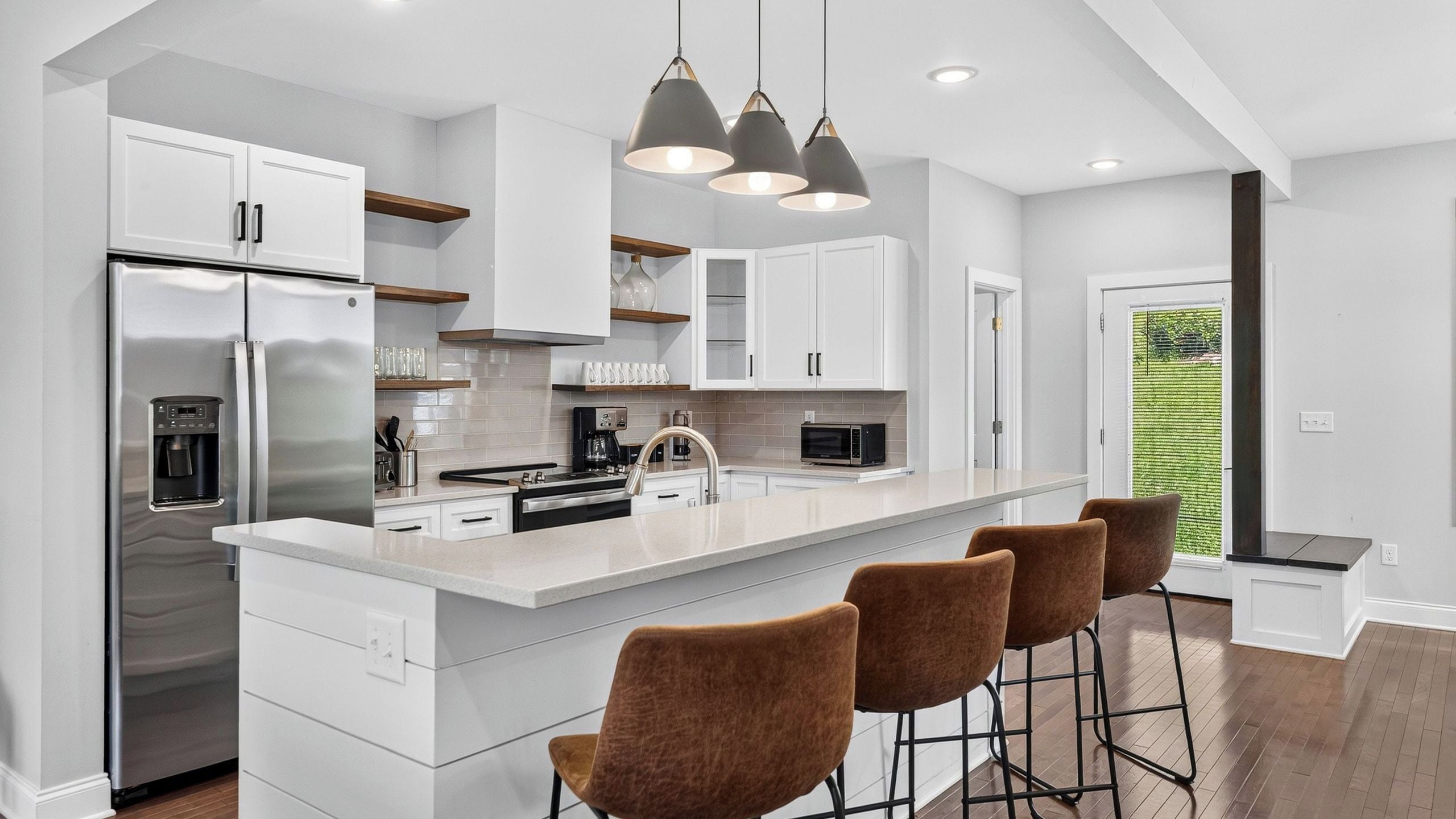 A modern kitchen with a large island, stainless steel appliances, and bar stools.