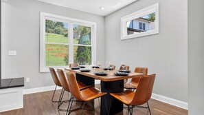 A dining area with a rectangular table set for four, surrounded by six brown chairs. - Riverside House by Avantstay French Broad River Views Balcony Near DT + Silver Line Park (Asheville)