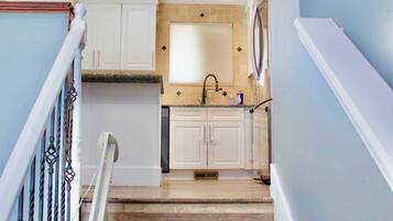 A staircase leading to a kitchen with white cabinets and a wooden floor.