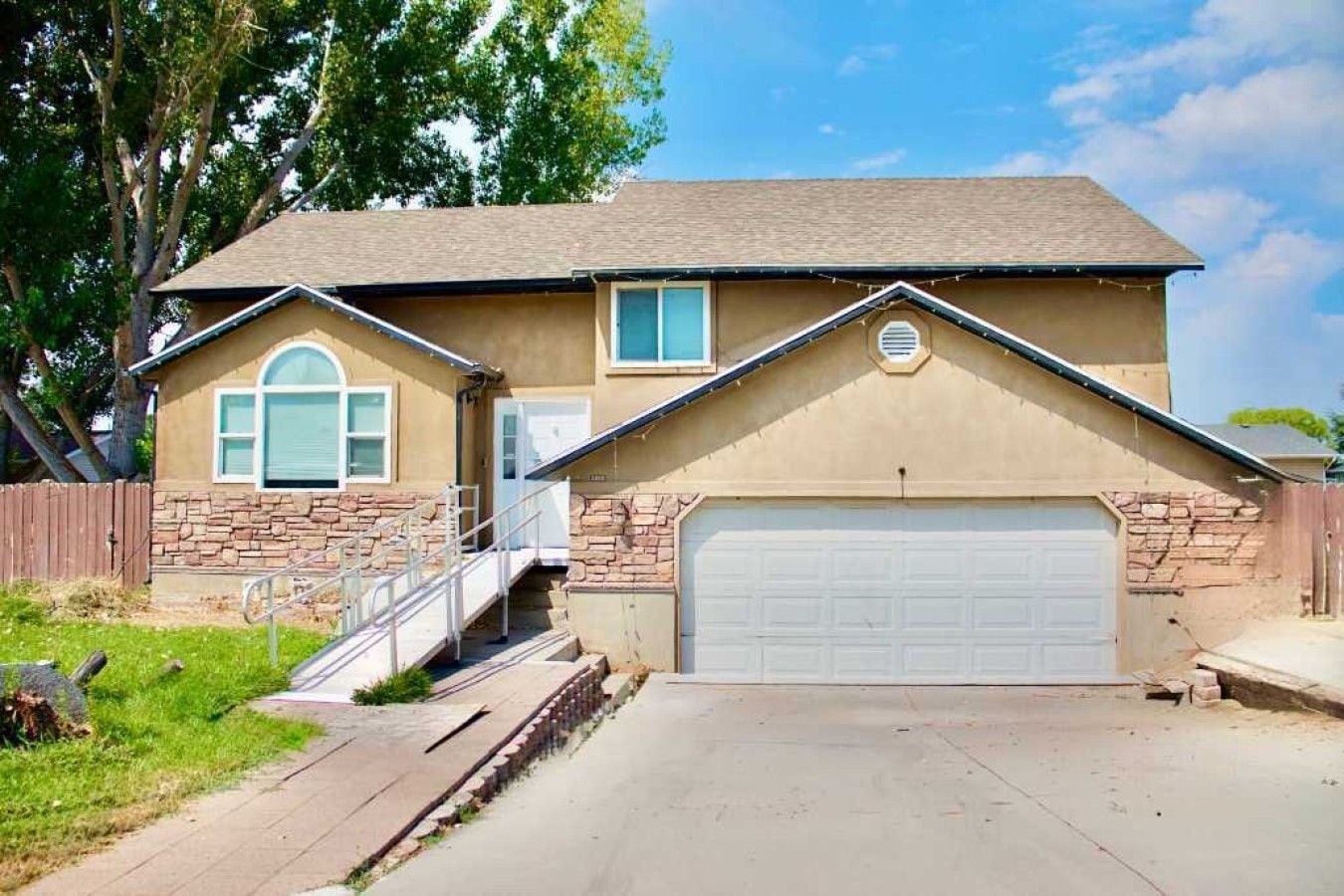 A single-story house with a garage, a front porch, and a stone foundation.