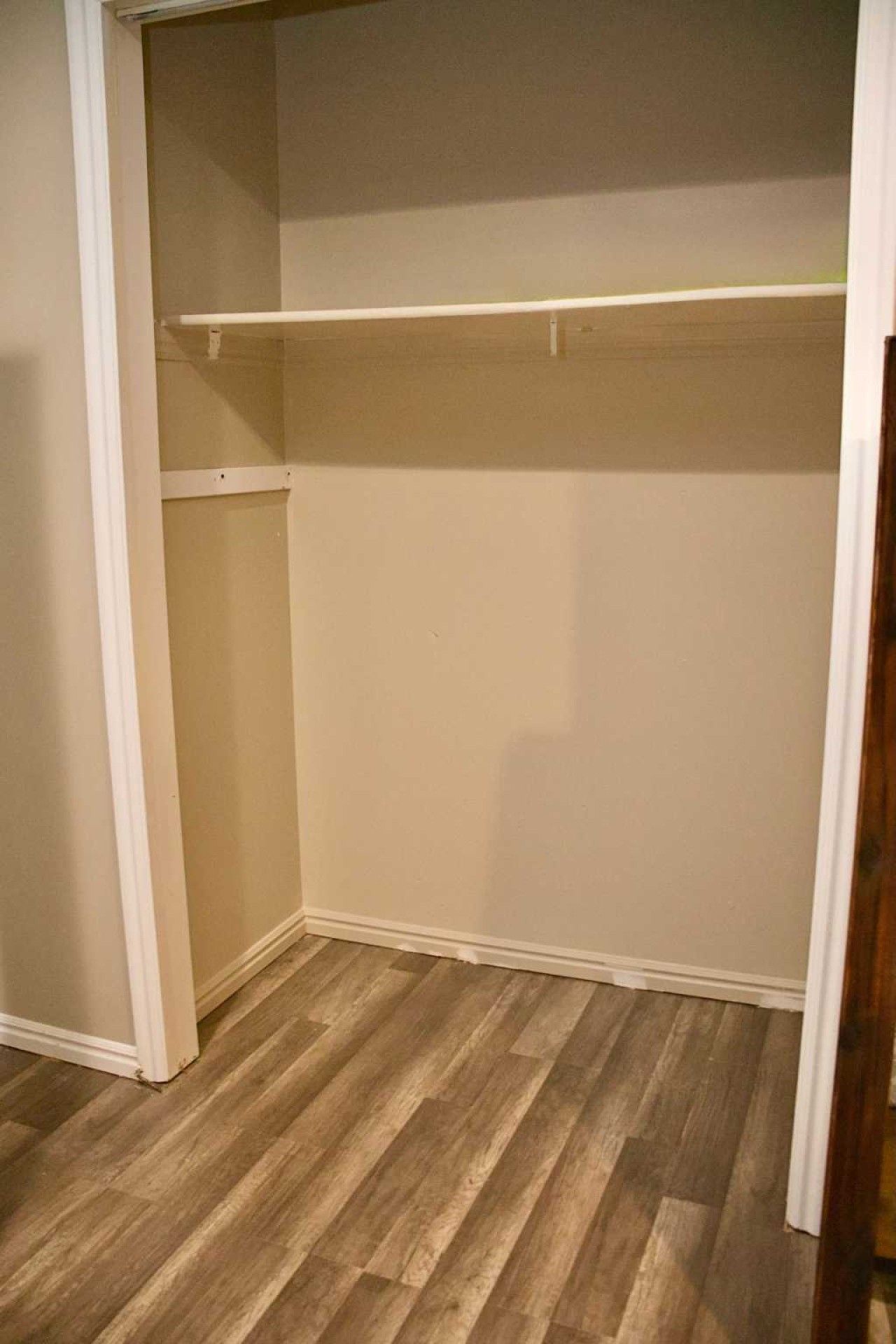 A closet with wooden flooring and white walls.