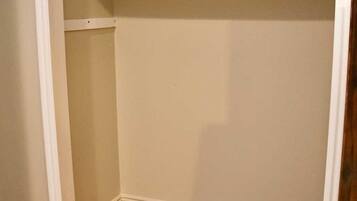A closet with wooden flooring and white walls.