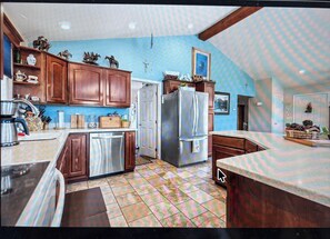 A kitchen with wooden cabinets, a stainless steel refrigerator, and a tiled floor. - 3-bedroom house with acreage for horses. Fire pit and Hot Tub. (Hot Springs)