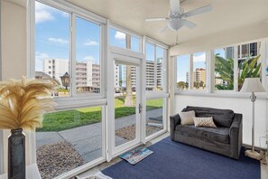 A room with a large window, a ceiling fan, a black sofa, and a lamp. - Venice Beach Getaway @ Gulf Point (Venice)