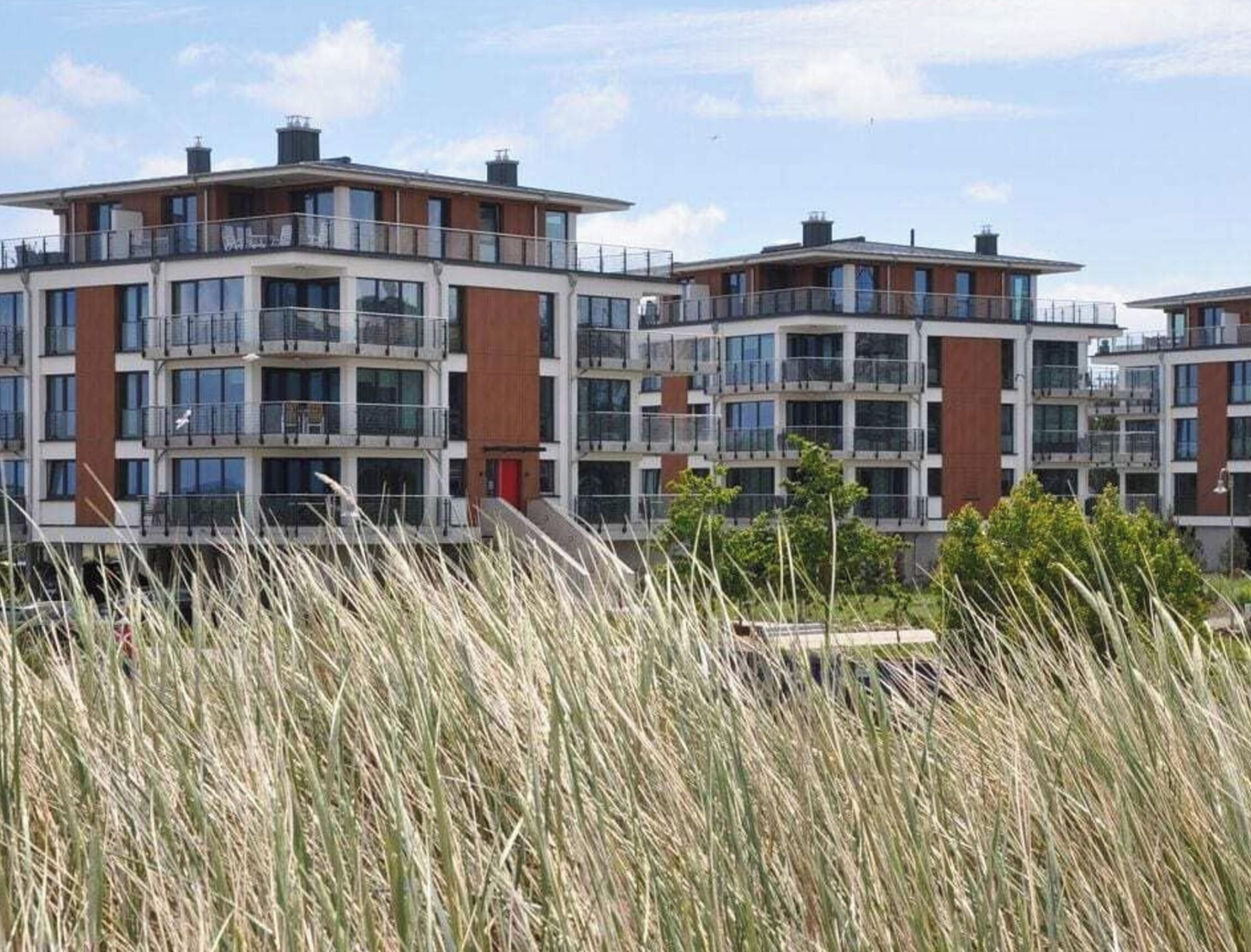 Un edificio residencial de varios pisos con balcones, ventanas amplias y techo plano.
