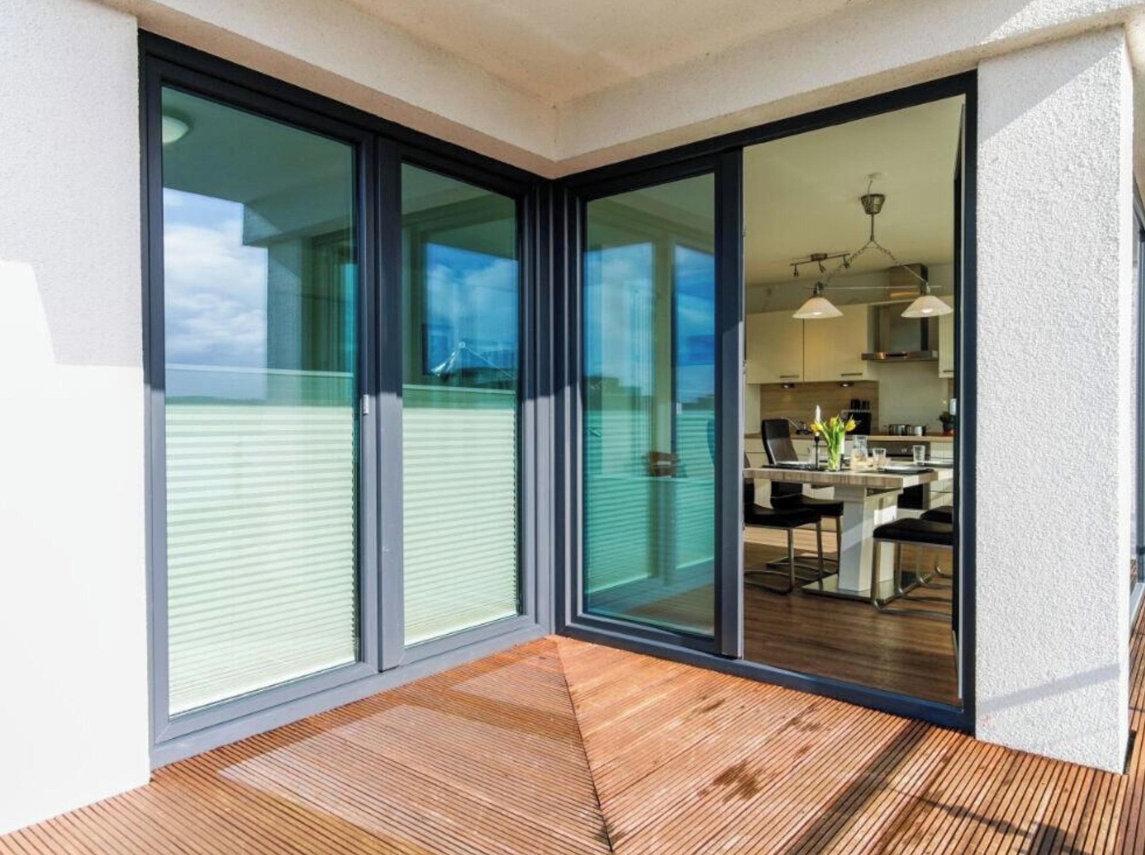 A modern interior with a sliding glass door leading to a balcony with a wooden floor.