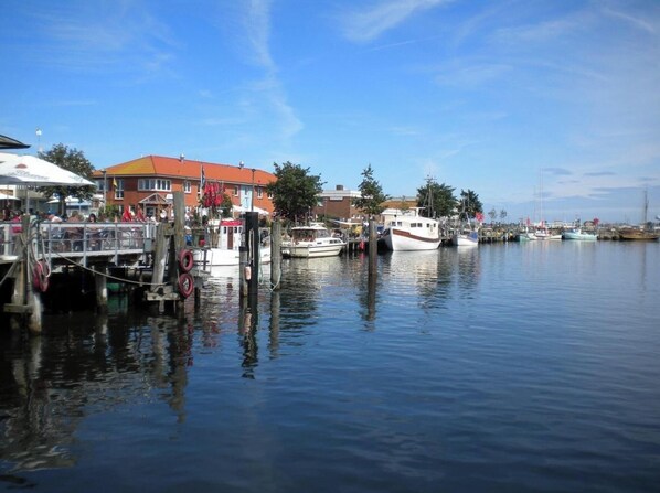 A marina with boats docked, a building with a red roof, and a clear blue sky. - Holiday Apartment With 2 Bedrooms (Heiligenhafen)