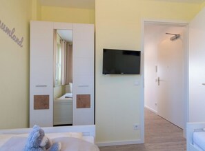A bedroom with a bed, a television mounted on the wall, and a door leading to another room. - Holiday Apartment With 2 Bedrooms (Heiligenhafen)
