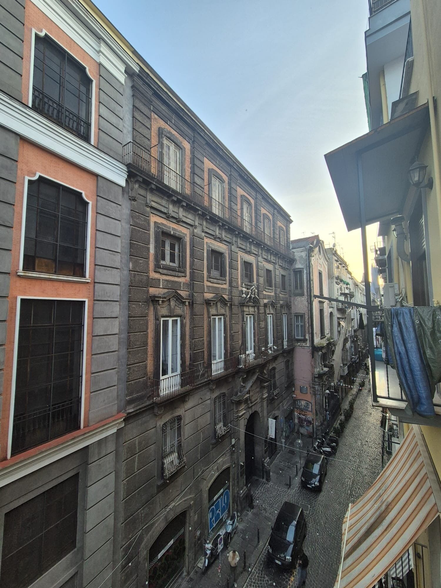 Una calle estrecha flanqueada por edificios, con numerosas ventanas y balcones.