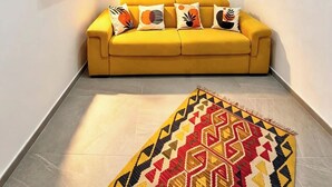 A narrow hallway with a yellow sofa, a patterned rug, and a blue artwork on the wall. - RODA Apartments (Napoli)