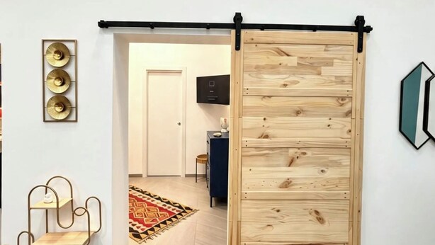 A room with a sliding wooden door, a metal-framed shelf, and a wall-mounted light fixture. - RODA Apartments (Napoli)