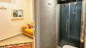 A bathroom with a shower, toilet, bidet, and a patterned rug. - RODA Apartments (Napoli)