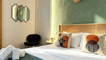 A hotel room with a green quilted bedspread, a neatly made bed with white linens, a headboard with decorative elements, and a wall-mounted mirror.