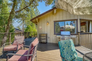 Wooden outdoor deck with patio seating, a barbecue grill, and surrounding forest views. - Cozy Yosemite Cabin with Lake & Mountain Fun (Groveland)