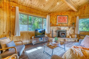 Living room with wood-paneled walls, stone fireplace, and television. - Cozy Yosemite Cabin with Lake & Mountain Fun (Groveland)