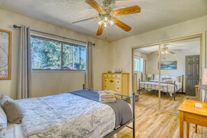 A bedroom with mirrored closet doors, a metal-frame bed, and a ceiling fan. - Cozy Yosemite Cabin with Lake & Mountain Fun (Groveland)