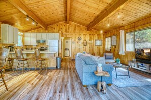 Open-concept living room and kitchen featuring wood-paneled walls and vaulted ceilings. - Cozy Yosemite Cabin with Lake & Mountain Fun (Groveland)