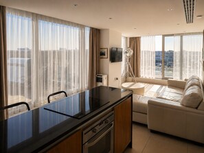 A modern kitchen with a central island, a sofa, and a dining area with chairs. - Sidemersey Livings-Unmatched Views, Secure Parking (Liverpool)