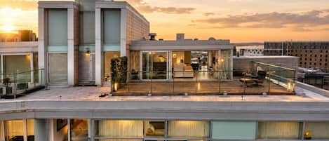 A modern building with multiple floors, large windows, and a rooftop terrace.