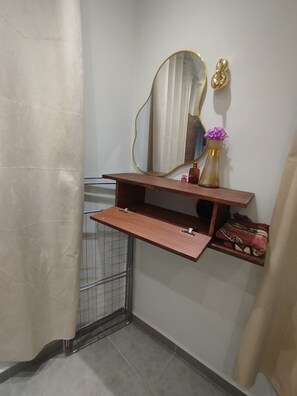 A bathroom with a wooden vanity, a mirror with a gold frame, a vase with flowers, and a towel rack. - 🌊 New studio apartment in Martil • Self-Check-in • Secure residential complex (Martil)