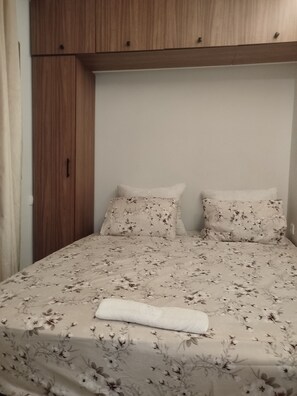 A bedroom with a bed, two pillows, a wooden wardrobe, and a white wall. - 🌊 New studio apartment in Martil • Self-Check-in • Secure residential complex (Martil)