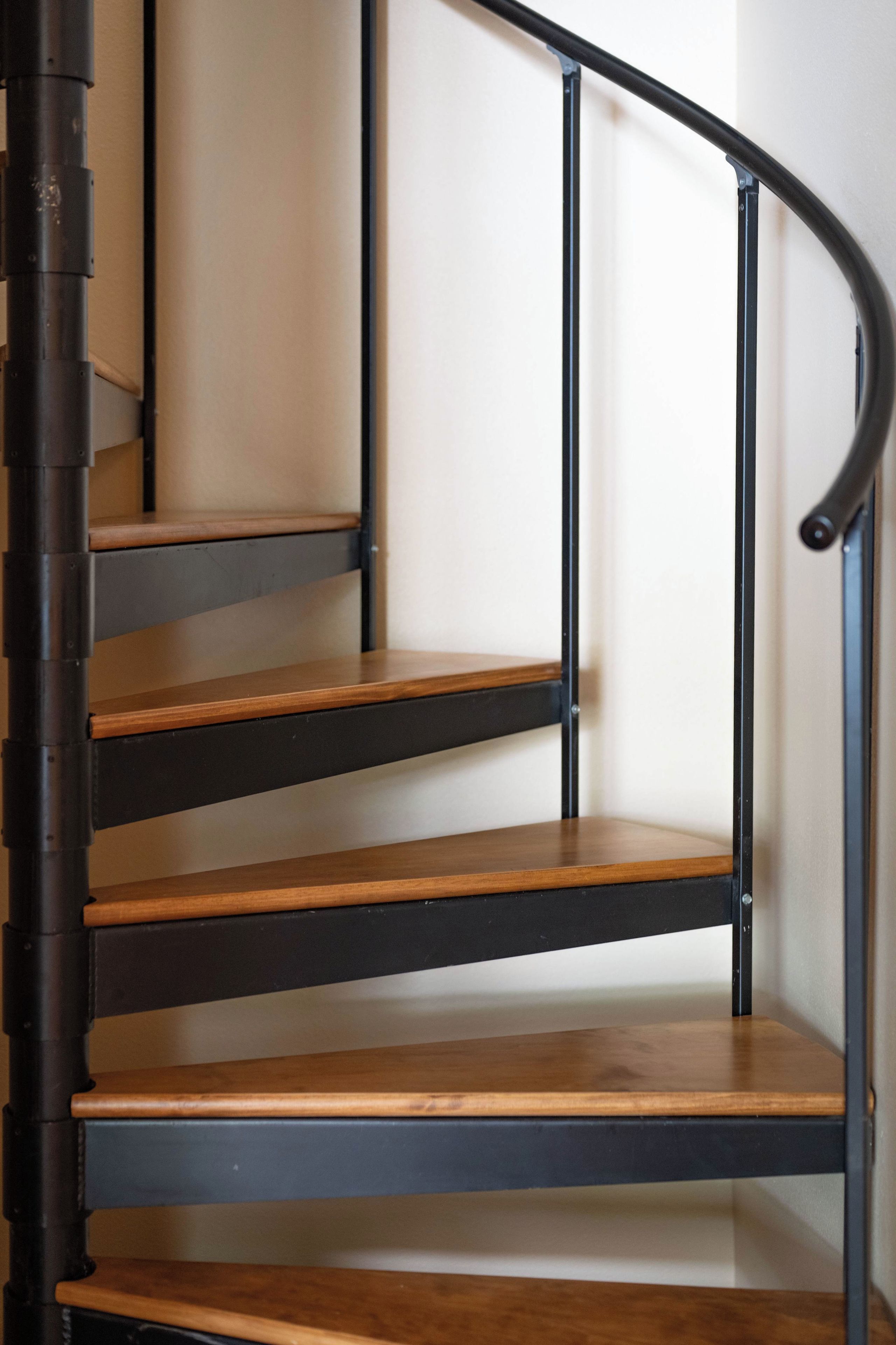 A spiral staircase with wooden steps and black metal railings.