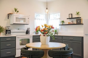Una cocina moderna con una mesa de comedor redonda, armarios oscuros y un microondas blanco.