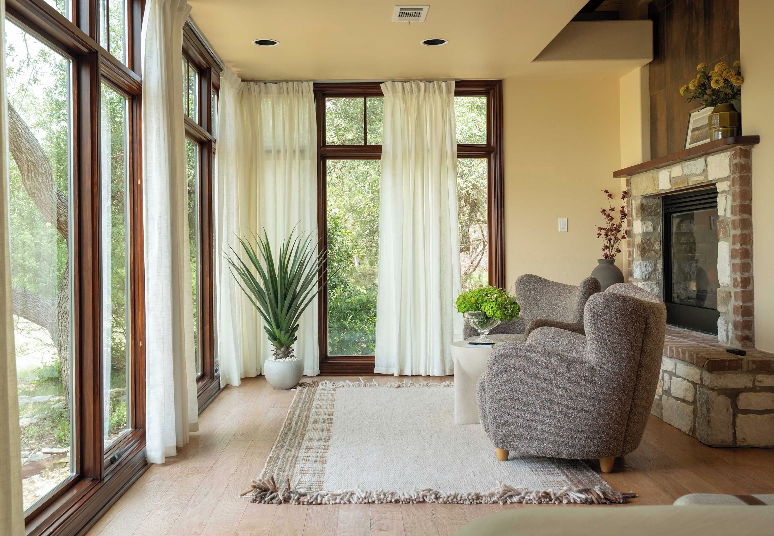 A living room with large windows, a fireplace, and a comfortable armchair.