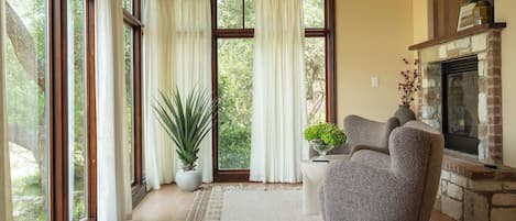 Una sala de estar con ventanas amplias, chimenea y un sillón cómodo.